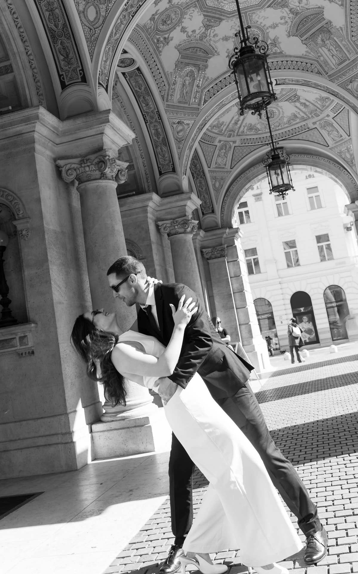 Groom dipping the bride in the colonnade of a classical building
