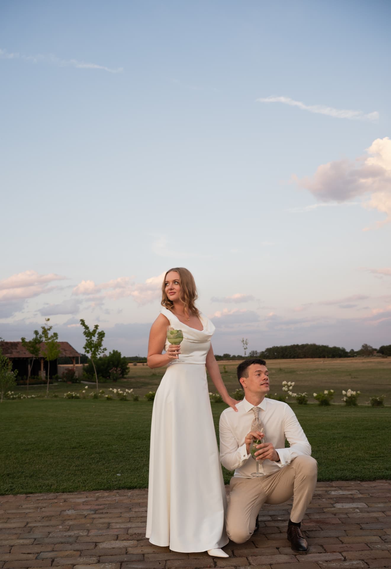 Bride and groom with drinks in a meadow at golden hour