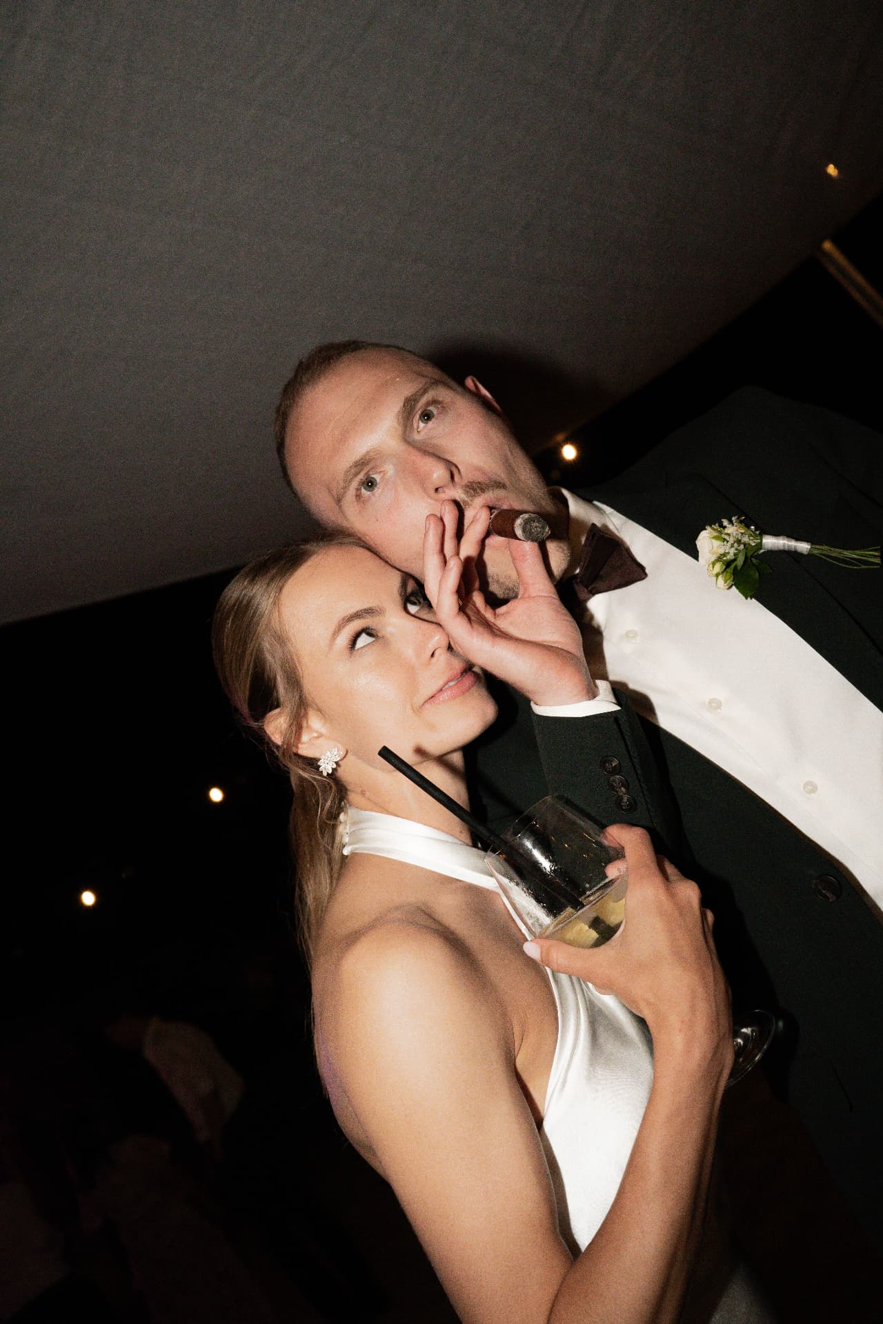 Bride and groom with a cigar and drinks late at the reception