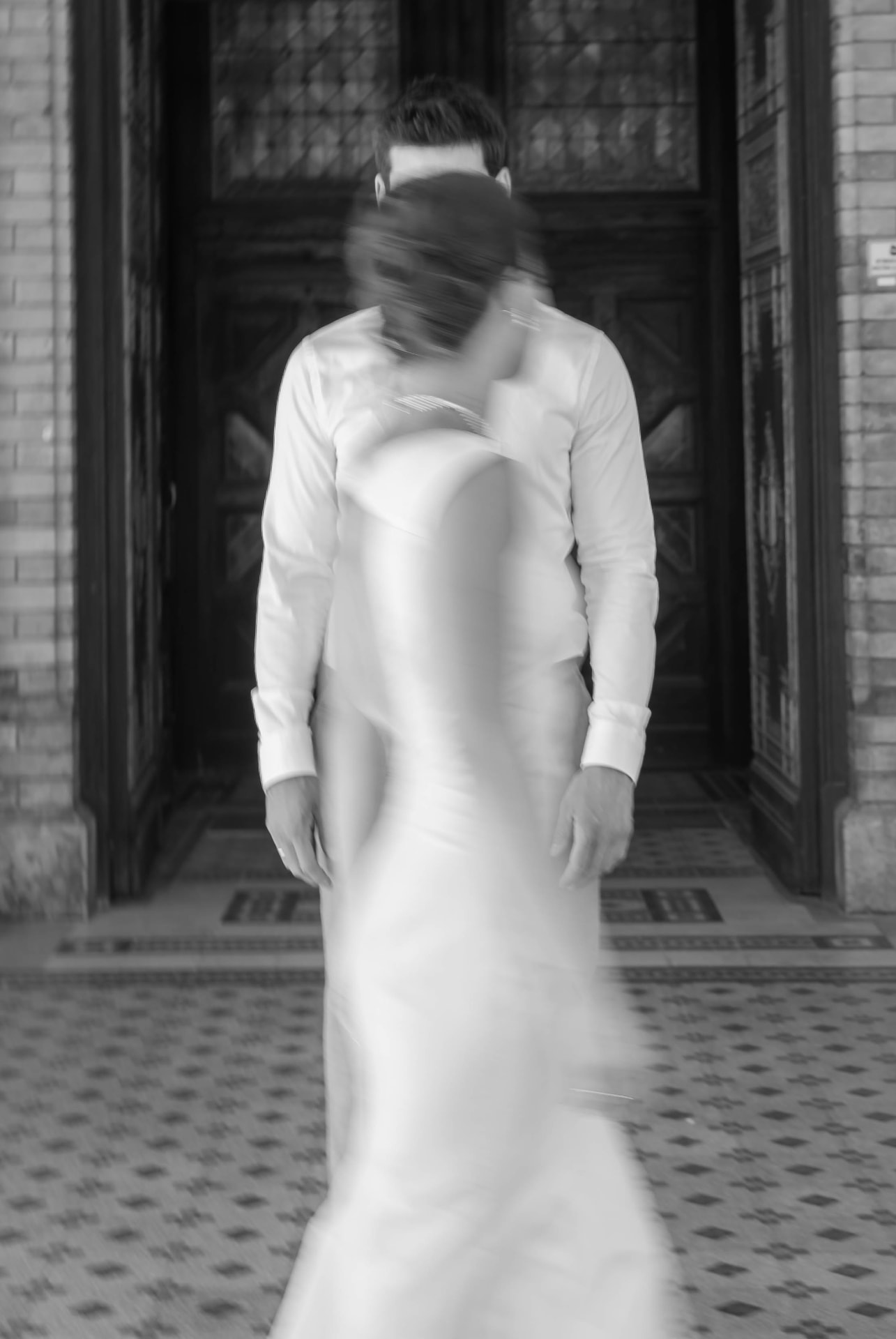 Motion-blurred black and white portrait of the couple in a doorway