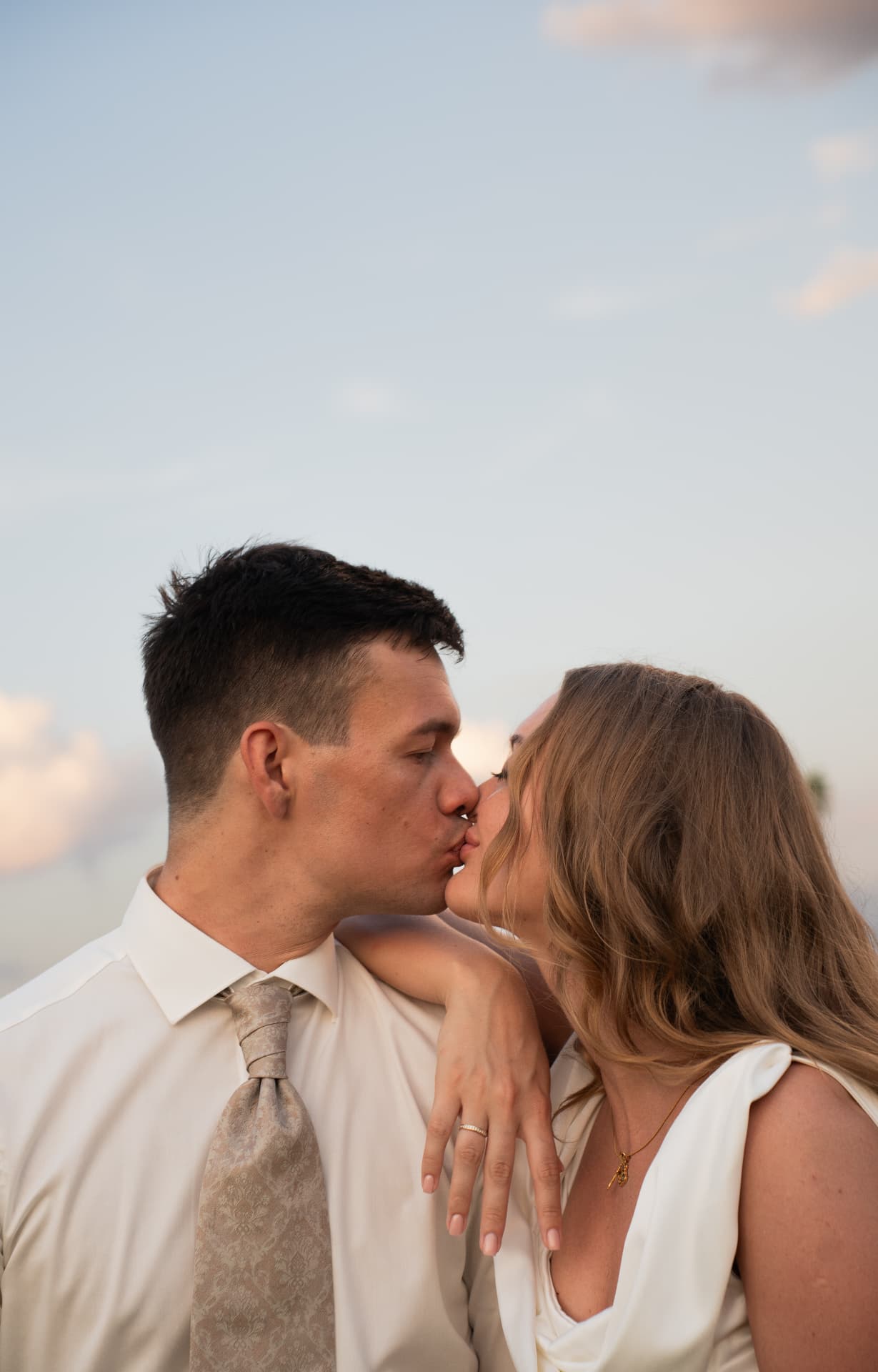 Couple kissing against a soft sunset sky