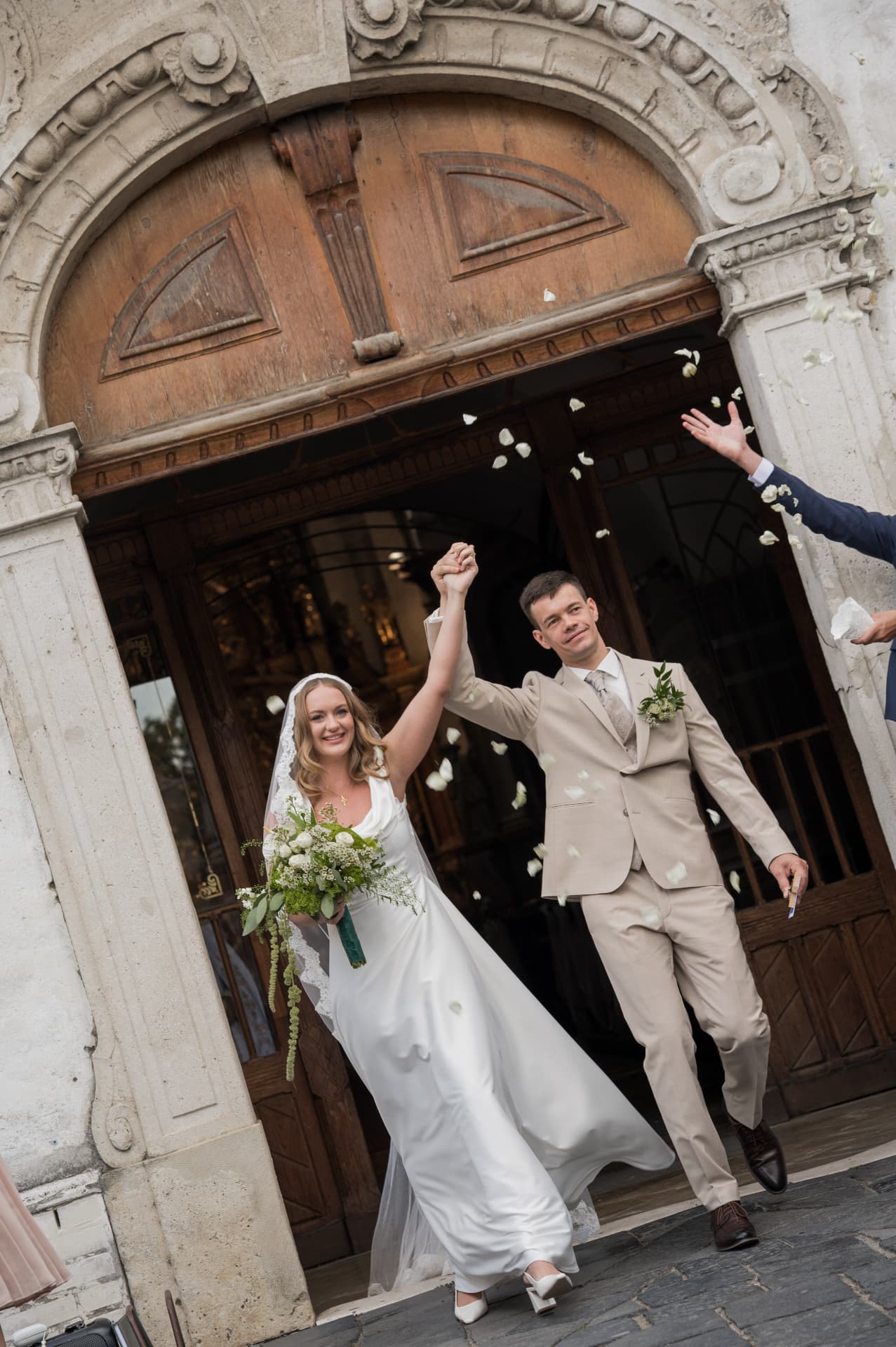 Newlyweds cheering as they leave the church under a shower of petals