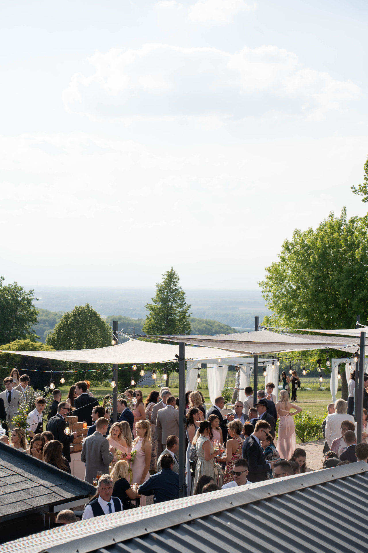Outdoor wedding reception with string lights, guests on the hillside
