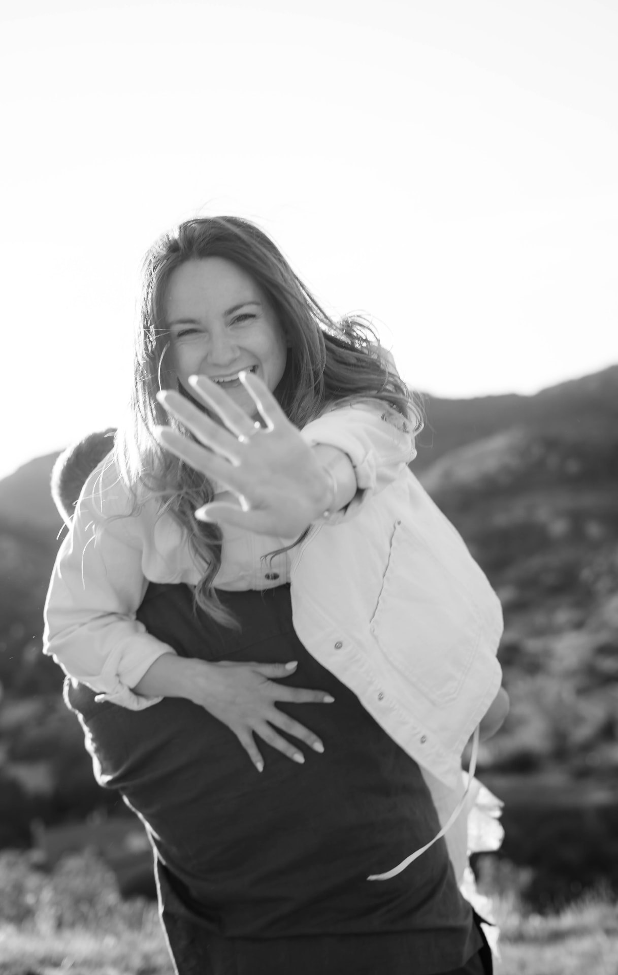 Couple laughing in nature, black and white, reaching for the camera